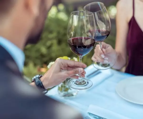 happy couple having romantic date, sitting at table in restaurant and clinking glasses